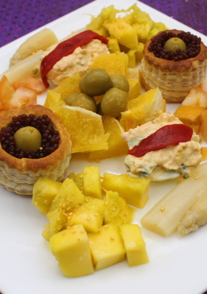Una foto de Volovanes y huevos rellenos acompañados de naranja, mango y espárragos