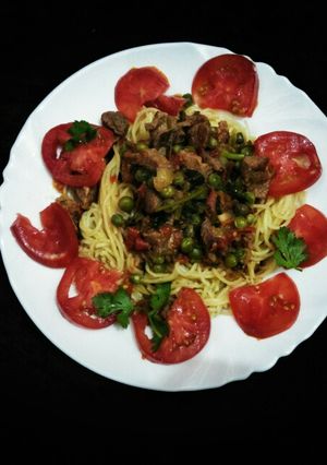 A picture of Stewed beef with green peas and spaghetti.