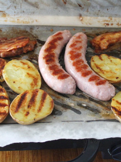 Una foto de Salchichas y panceta con patatas al grill doble