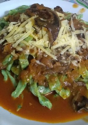 Una foto de Tallarines de espinaca con salsa roja y hongos de pino