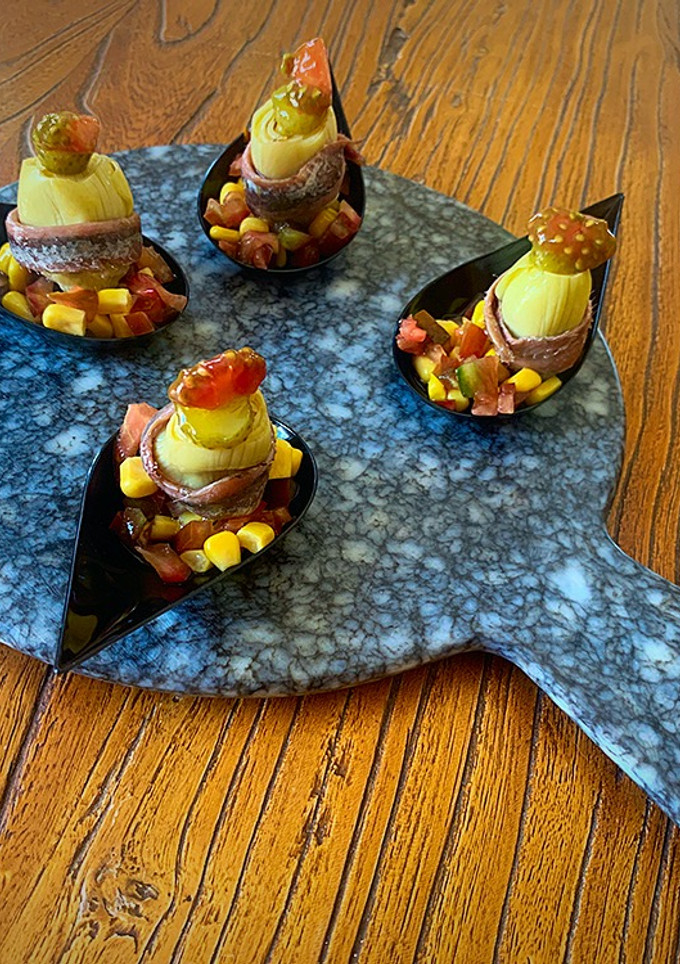 Una foto de Cuchara de alcachofa, anchoa, millo y tomate