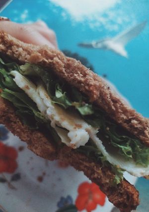 Hình của món Bữa sáng đơn giản với bánh mì đen kẹp trứng ốp và xà lách.