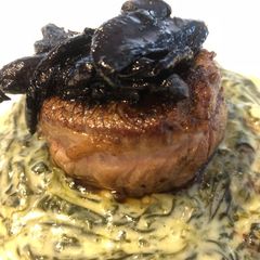 A picture of Beef filet on creamed spinach, topped with oyster mushrooms.