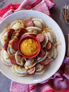 A picture of Perogies with Kielbasa, Onion, and Hot Mustard.