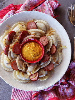A picture of Perogies with Kielbasa, Onion, and Hot Mustard.