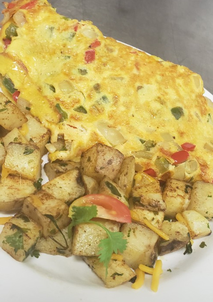 Una foto de Tortilla de huevo rellena con tres carnes + vegetales, papas asada