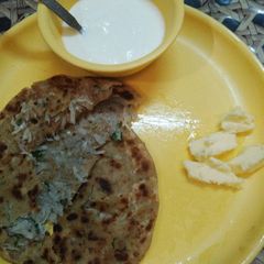 A picture of Muli de parathe with batter and dahi.