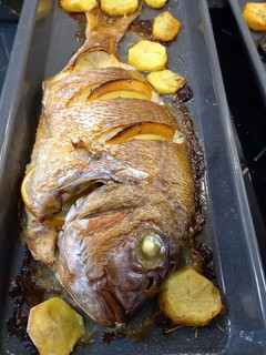 Una foto de Pargo Rosado con guarnición de patatas y cebollas horneadas