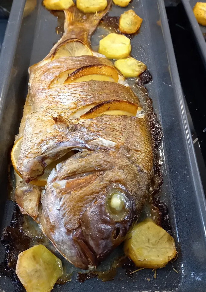 Una foto de Pargo Rosado con guarnición de patatas y cebollas horneadas