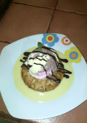 Una foto de Piñas flambeadas en espejo de salsa inglesa y helado.