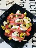 Ensalada de tomate, mozzarella, aguacate y anchoas, con albahaca fresca y regada con Aceite oliva