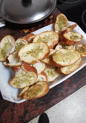 Una foto de Pan de pueblo tostado al horno con aceite de ajo y perejil