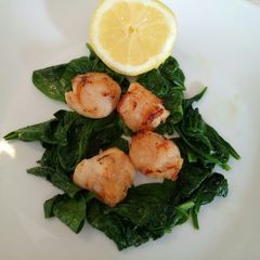 A picture of Pan fried scallops with wilted spinach.