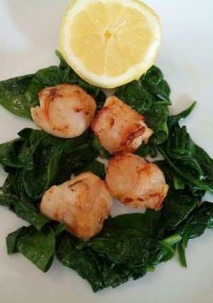 A picture of Pan fried scallops with wilted spinach.