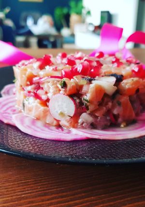 Une photo de Tartare de saumon, radis roses, baies roses et grenade