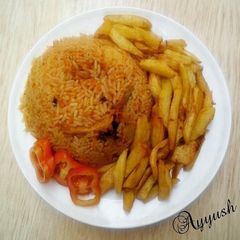 A picture of Jollofrice,with fried Irish potatoes and tomatoes.