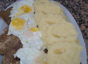 Una foto de Milanesas a caballo con puré de papas cremoso