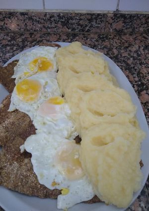 Una foto de Milanesas a caballo con puré de papas cremoso