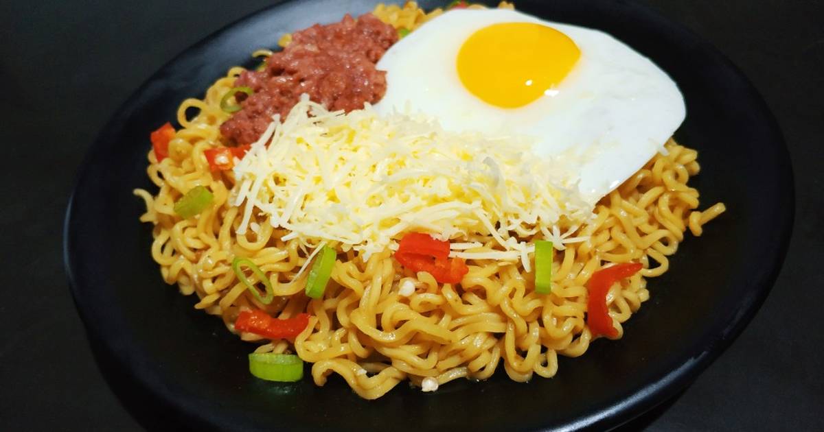 Semangkuk mie goreng keju dengan keju cheddar parut yang meleleh sempurna, dilengkapi topping daun bawang dan cabai iris