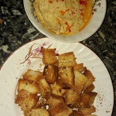A picture of Crispy bread squares grilled with hummus.