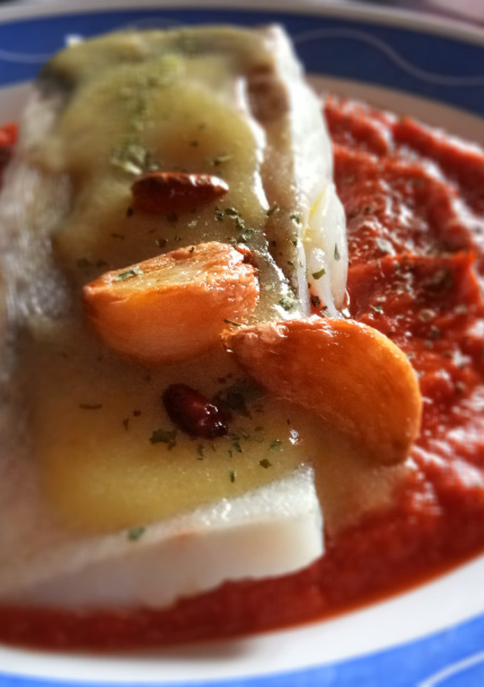 Una foto de Bacalao confitado con salsa de tomate cubierto de su Pil Pil