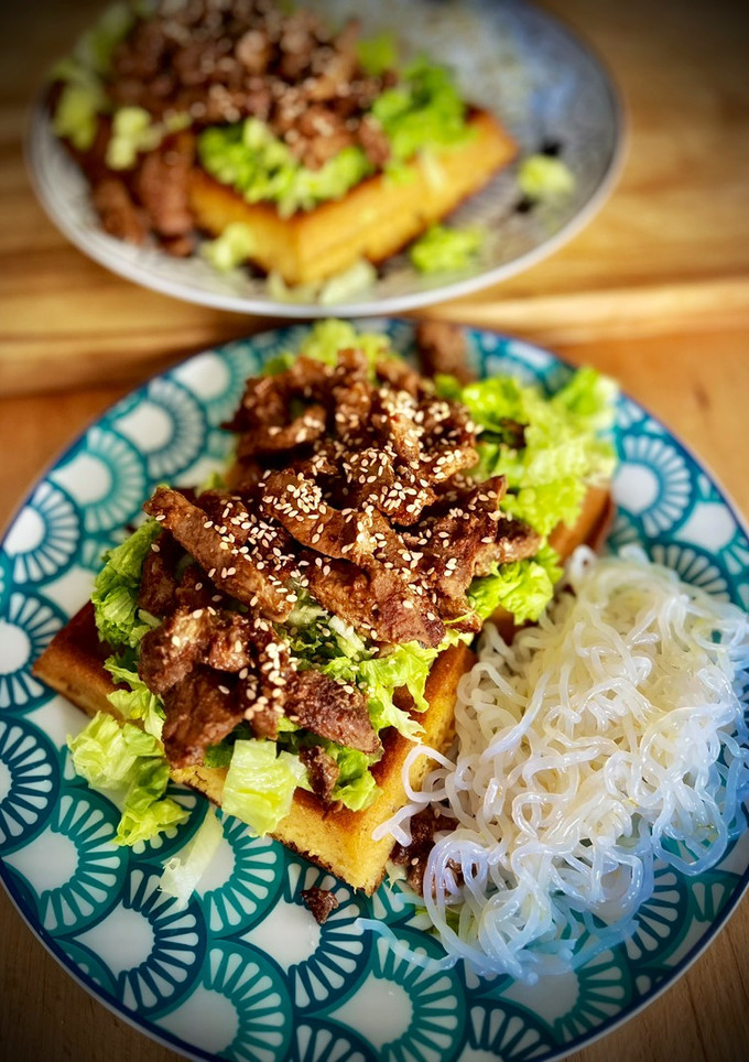 Una foto de Ternera en salsa hoisin sobre gofre de kéfir y fideos konjac