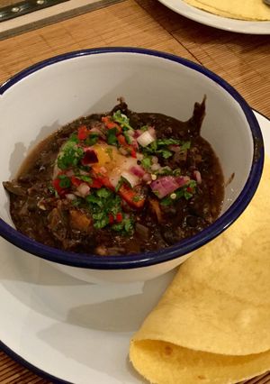 A picture of Black bean soup with poached egg, salsa and corn tortillas.