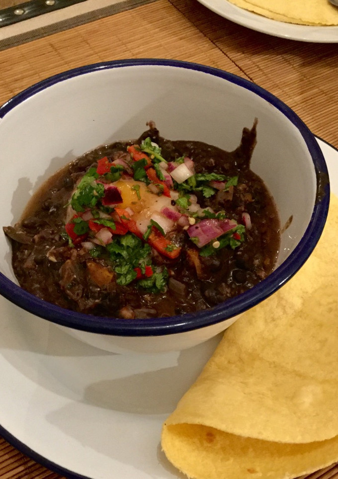 A picture of Black bean soup with poached egg, salsa and corn tortillas.