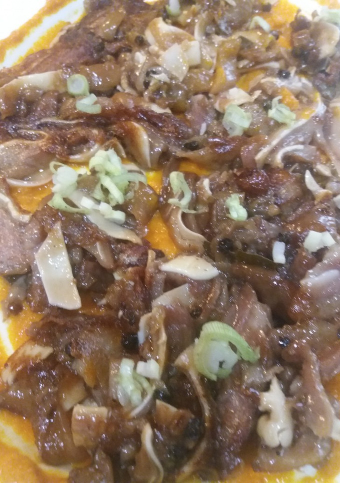 Una foto de Oreja de cerdo sobre brava y cebollita japonesa