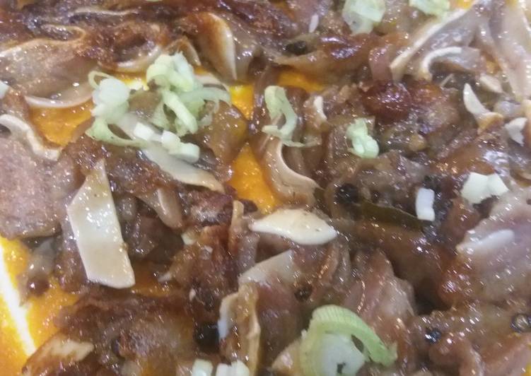 Oreja de cerdo sobre brava y cebollita japonesa