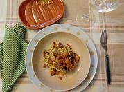 Una foto di pasta con speck affettato