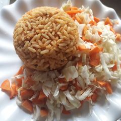 A picture of Jollof rice with cabbage and carrots.