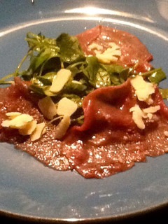 Una foto de Carpaccio de ternera con brotes tiernos de rúcula y parmesano