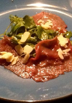 Una foto de Carpaccio de ternera con brotes tiernos de rúcula y parmesano