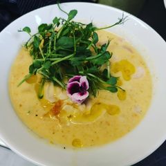 A picture of Creamy cheesy potatoes carrots soup served with shrimps.