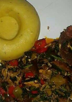 A picture of Pounded unripe plantain with assorted meat and vegetable soup.