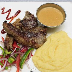 A picture of Grilled lamb, smashed potatoes and sauce.