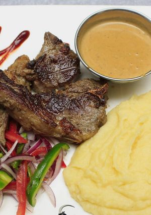 A picture of Grilled lamb, smashed potatoes and sauce.