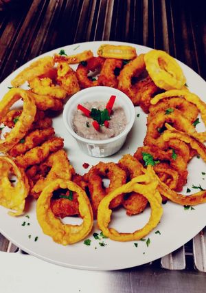 Una foto de Calamar a la romana con aros de cebolla y salsa de champiñones