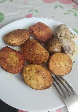Фото Запечена картопля половинками на дисковій сковороді на природі чи в духовці.