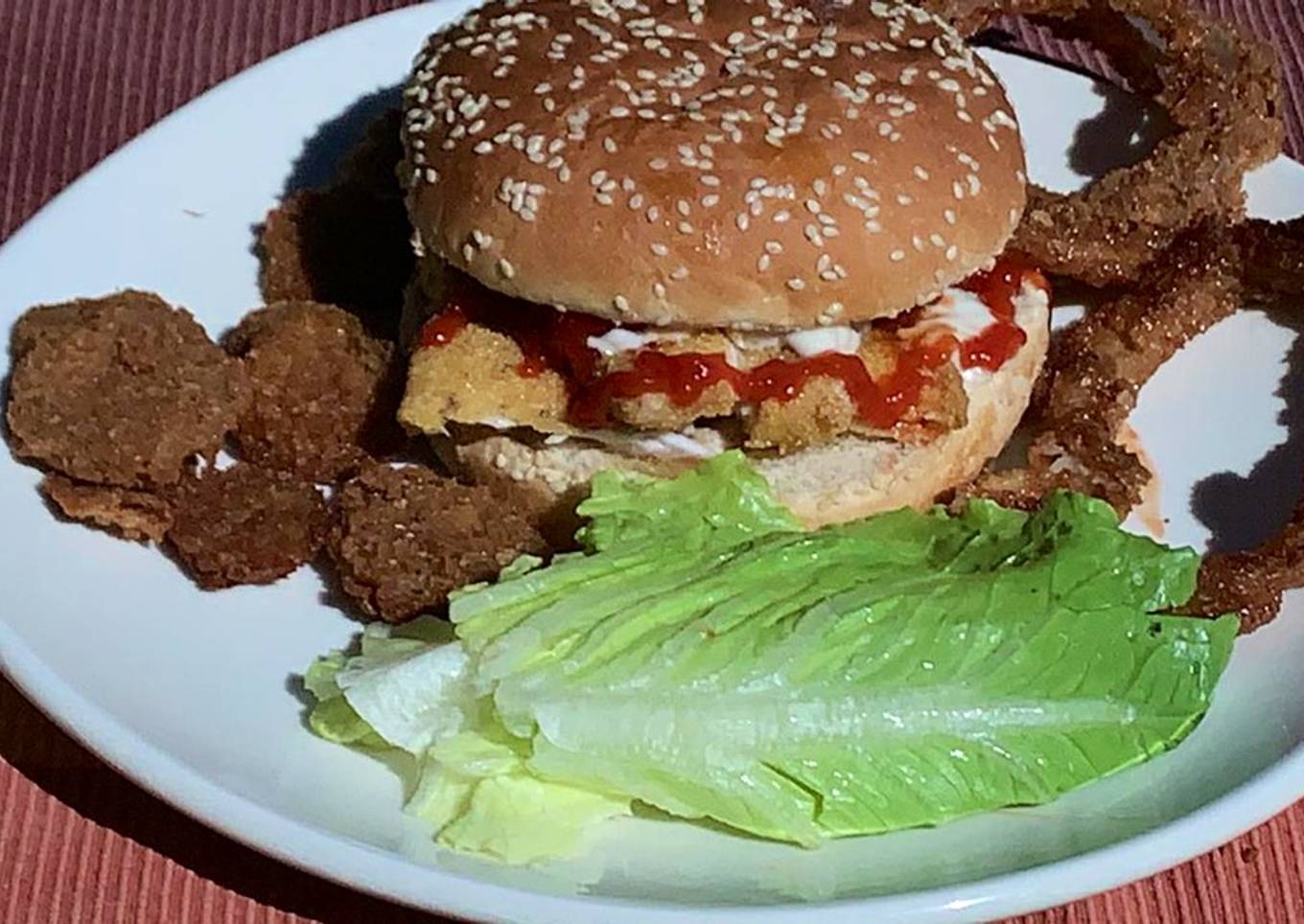 Hamburguesa de pescado estilo Sitka Alaska con guarnición de aros de cebolla y pepinillos fritos