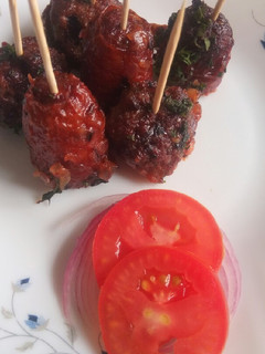 A picture of Meat balls and beef sausages bitings in sauce.