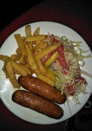 A picture of Sausage with few chips and salad.