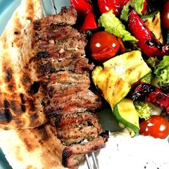 A picture of Lamb Souvlaki with grilled vegetables salad and tzatziki sauce.
