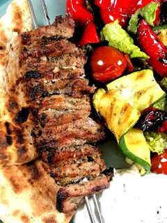 A picture of Lamb Souvlaki with grilled vegetables salad and tzatziki sauce.