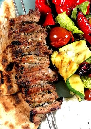 A picture of Lamb Souvlaki with grilled vegetables salad and tzatziki sauce.