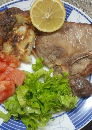 Una foto de Tortilla de papas con hierbas aromáticas. Chuletas de cerdo