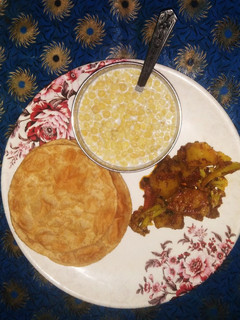 A picture of Aloo Gobi with Puri and Raita.