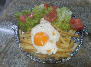 Una foto de Ensalada de Lechuga y Tomate con Papas Fritas y Huevo Frito