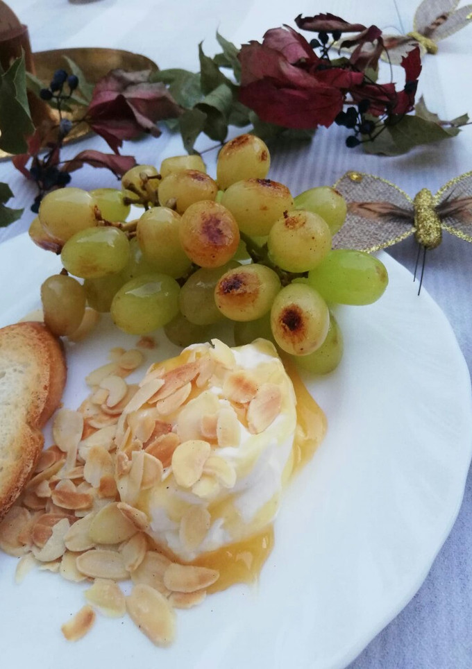 Una foto de Queso de cabra fresco con miel y uvas a la plancha
